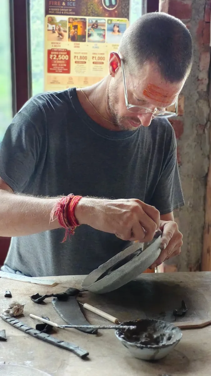 A guest hand-building a clay piece at the work table