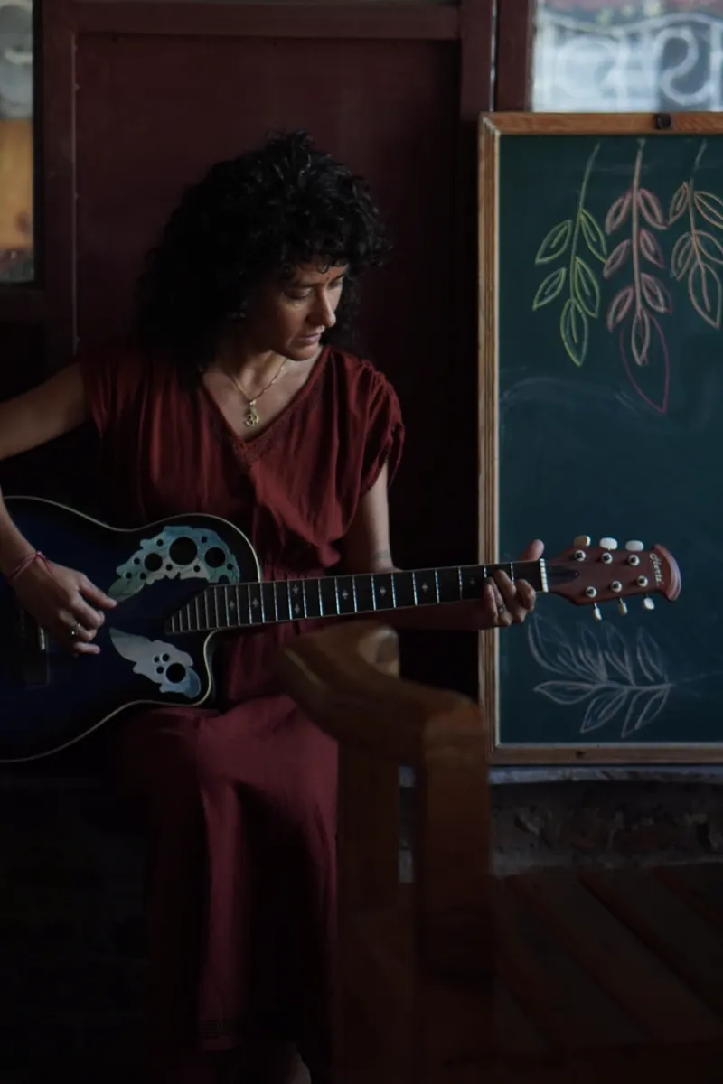 A guest playing guitar beside a chalkboard decorated with chalk-drawn leaves at Aavya Pottery & Art Studio