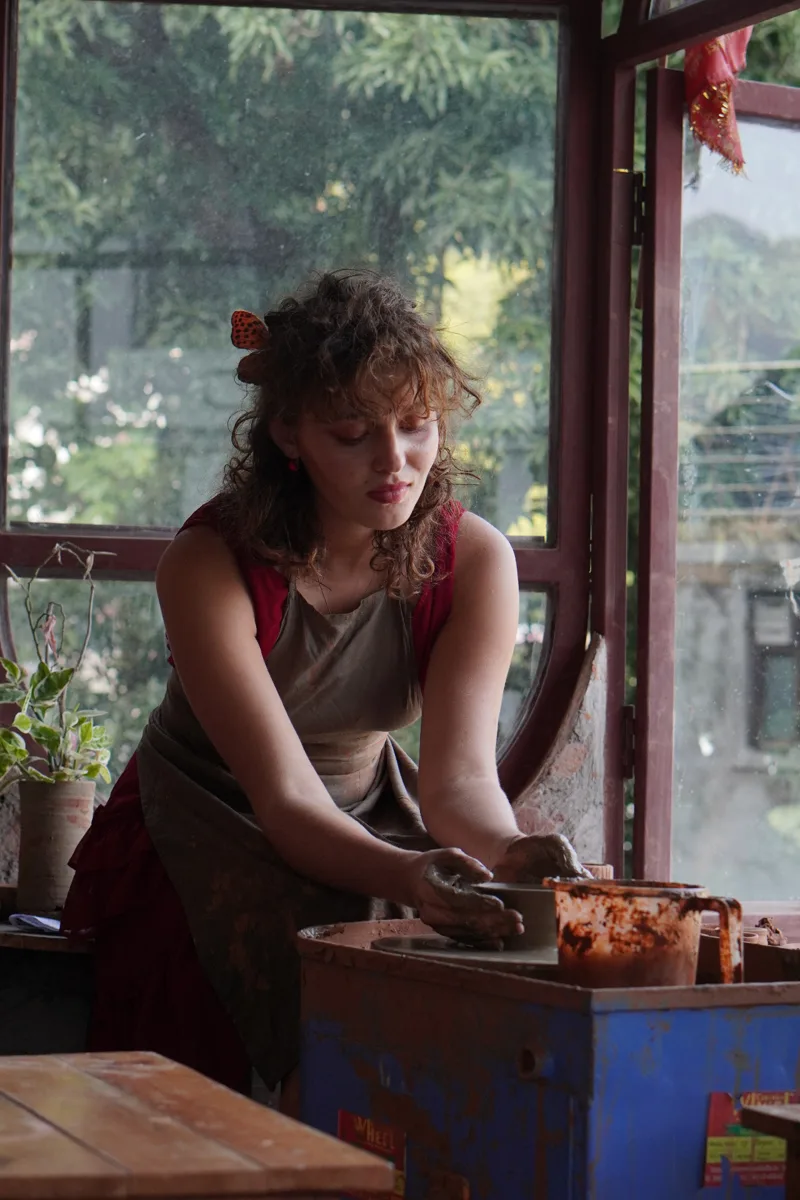 A guest working with clay beside the studio’s forest-facing windows