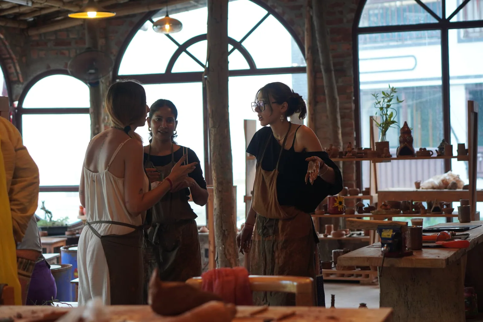 Guests chatting with clay-covered hands inside the Aavya Pottery & Art Studio