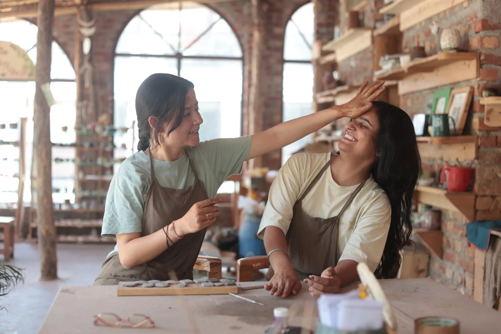 Two guests laughing together at the pottery table in the Aavya Pottery & Art Studio
