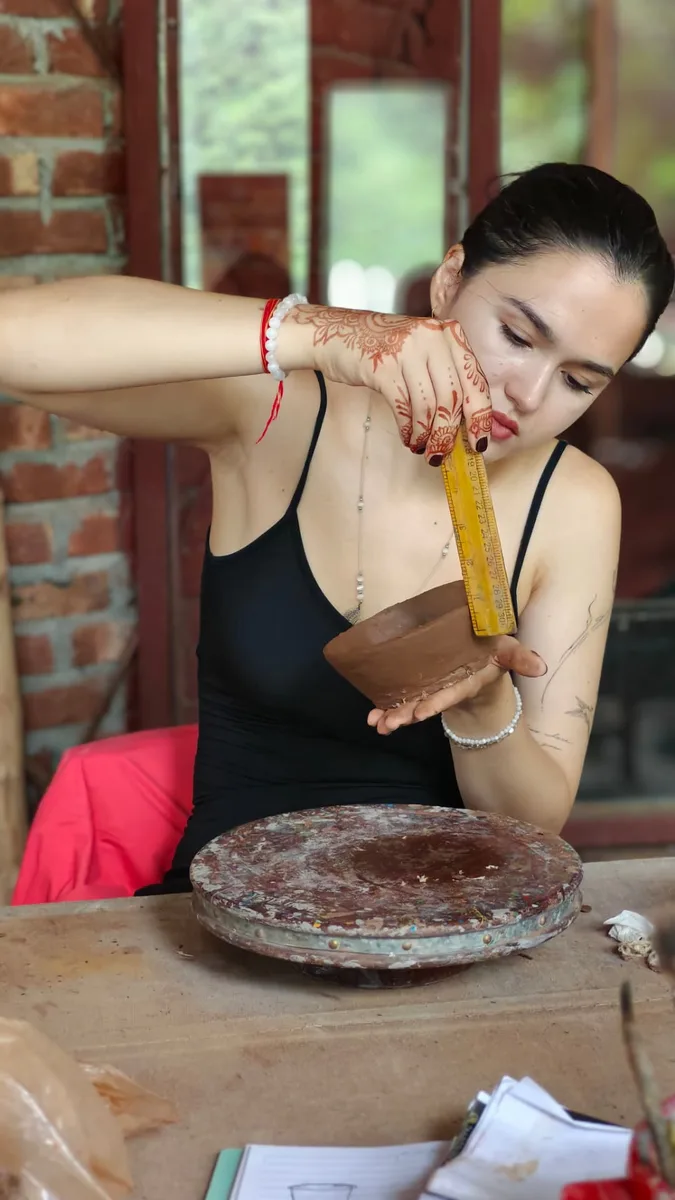 A guest measuring a hand-built clay bowl with a ruler