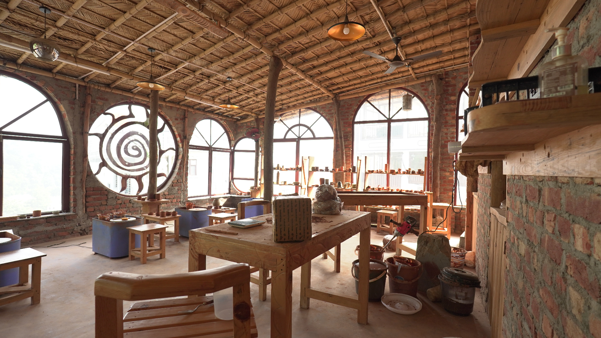 Pottery wheels and clay work beneath the studio's spiral sun windows