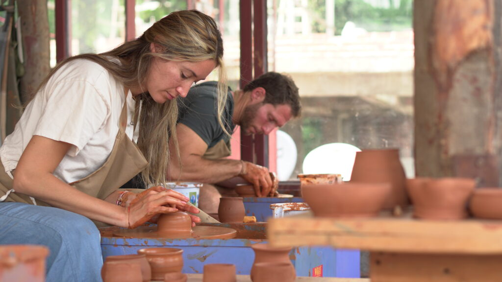 Two guests shaping clay on pottery wheels at Aavya's terrace studio in Rishikesh